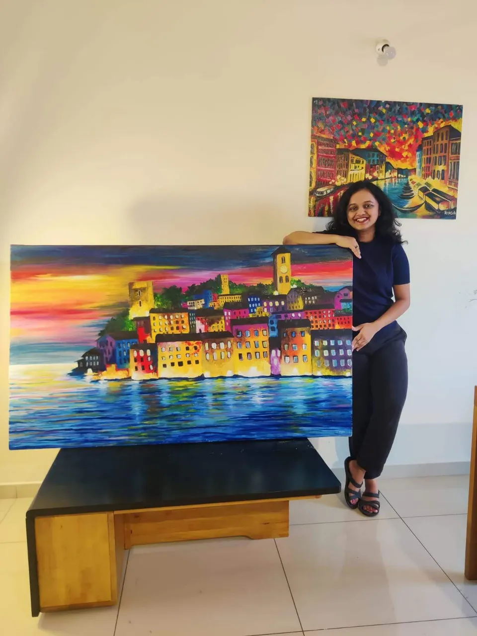 Priyasha holding her colourful Lakeside Town painting